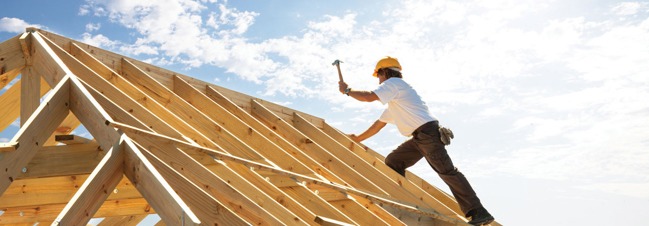 Construction worker building roof of house