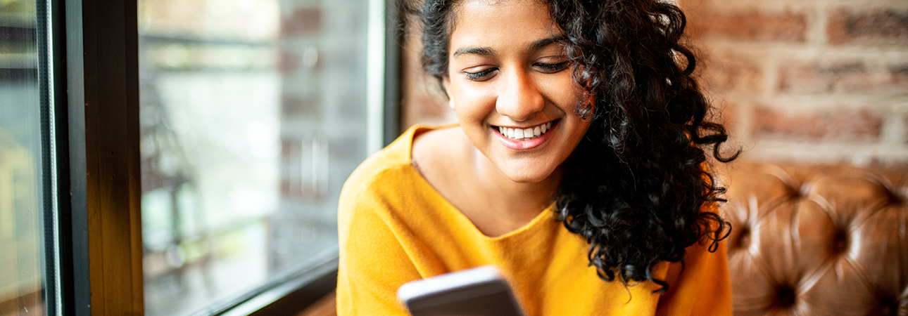Smiling young woman looking at phone screen